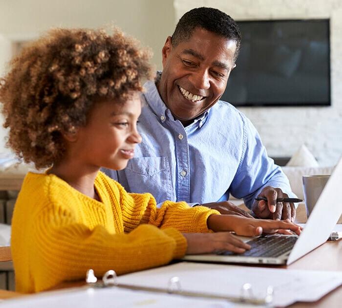 Parent helping his daughter with online school course on computer - Connections Academy